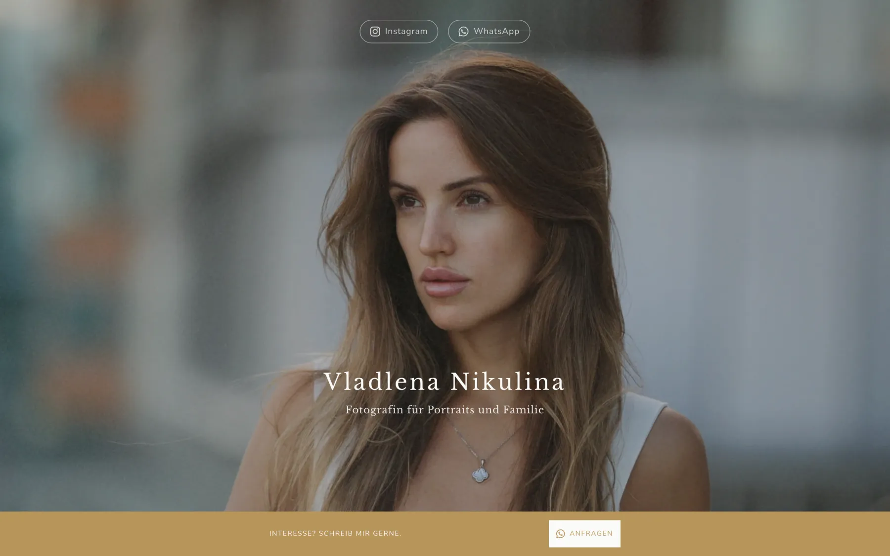 First screen of the site on a desktop: a full-width portrait with the name Vladlena Nikulina and “Fotografin für Portraits und Familie”, Instagram and WhatsApp buttons at the top, and a gold “Interesse? Schreib mir gerne.” bar with an “Anfragen” button at the bottom.